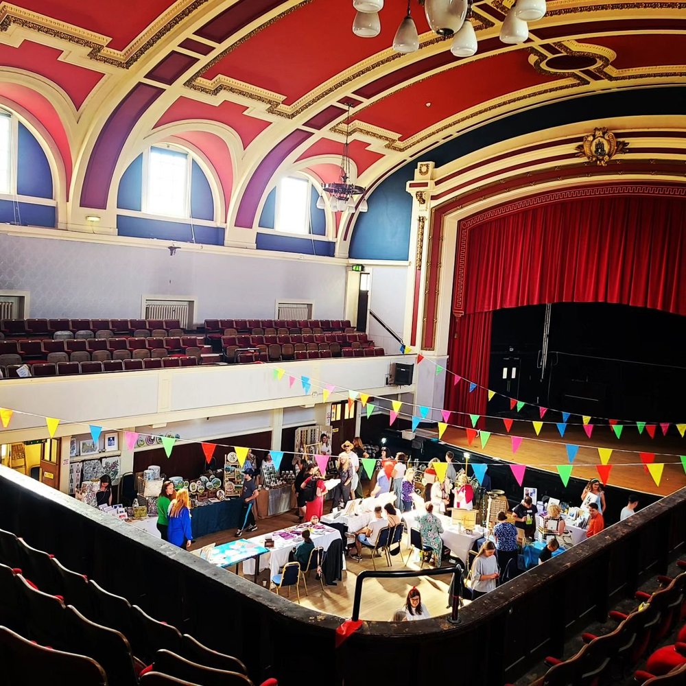 The Main Hall seen from the balcony, with tables set out on the floor and the stage to the right.